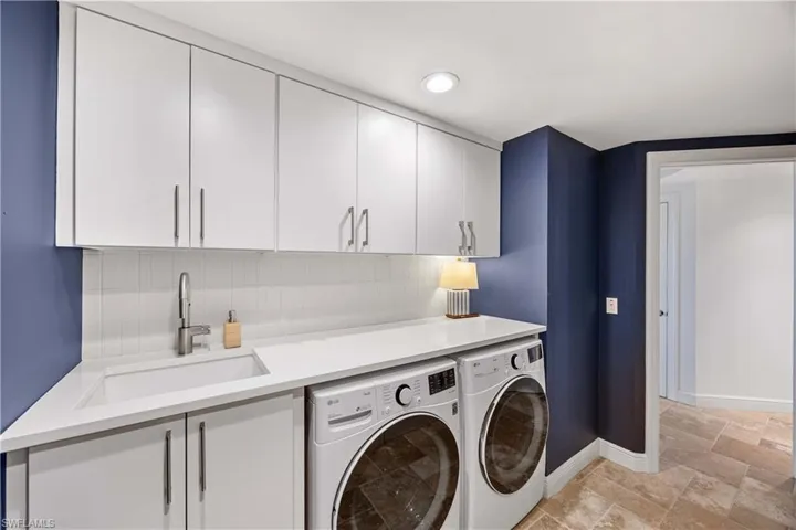 Washroom featuring separate washer and dryer, cabinet space, and light stone finish flooring