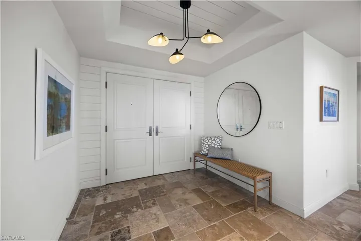 Foyer with a raised ceiling and stone tile flooring