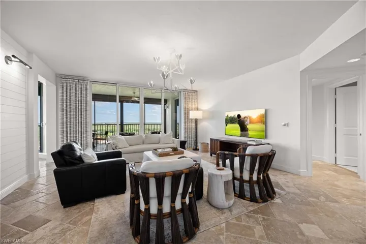 Living area featuring stone tile flooring, expansive windows, and a chandelier