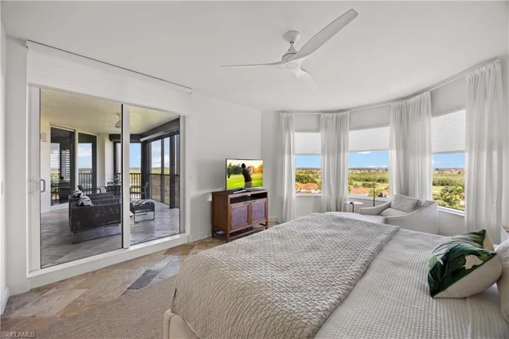 Bedroom with stone tile floors, access to outside, and a ceiling fan