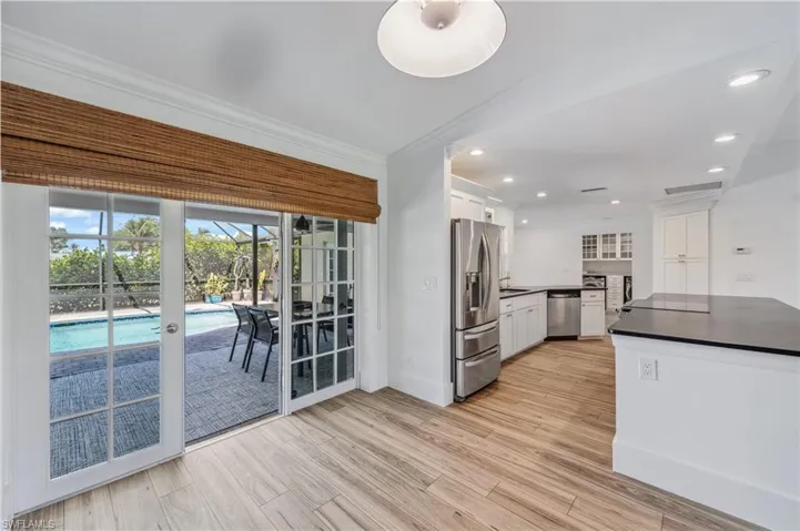 Kitchen featuring dark countertops, light wood finished floors, ornamental molding, white cabinets, and stainless steel appliances