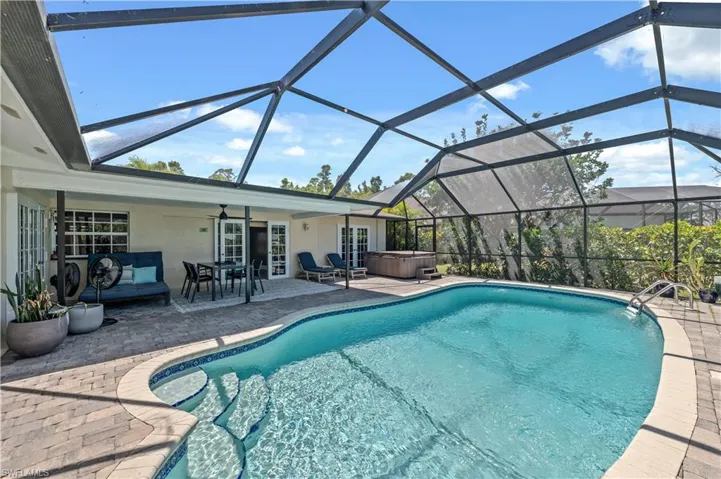 Outdoor pool with a hot tub, a lanai, french doors, a patio area, and a ceiling fan