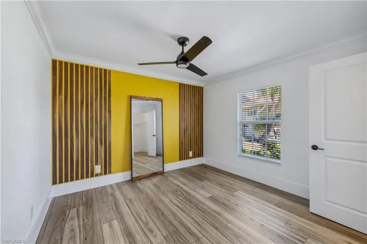 Unfurnished bedroom featuring a ceiling fan, light wood tile-type flooring, baseboards, and ornamental molding