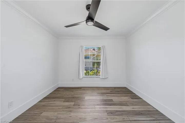 Spare room featuring baseboards, crown molding, a ceiling fan, and wood style tile finished floors