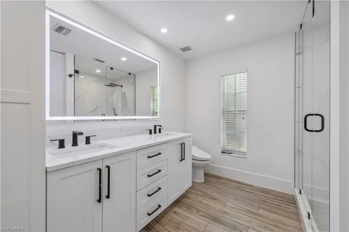 Bathroom featuring a marble finish shower, visible vents, and a sink