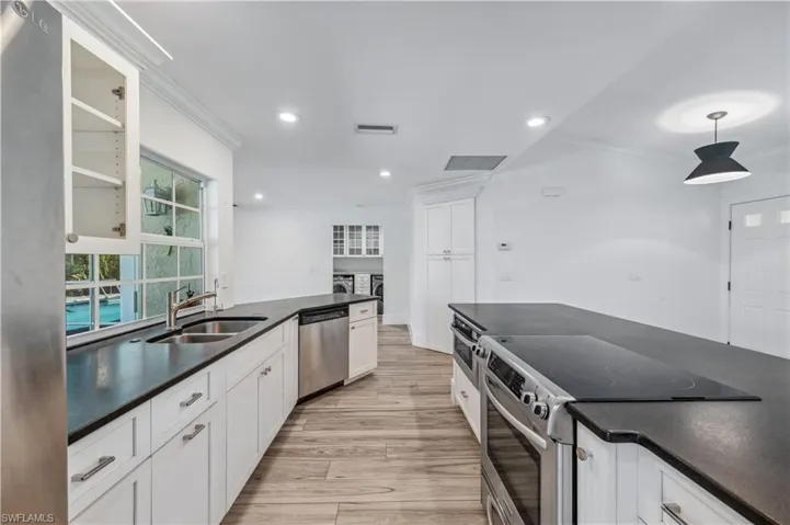 Kitchen with a sink, dark countertops, washing machine and clothes dryer, and stainless steel appliances