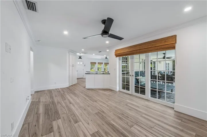 Unfurnished living room featuring light wood finished floors, visible vents, ceiling fan, and ornamental molding