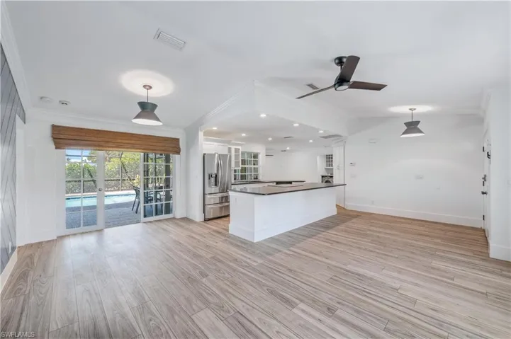 Kitchen featuring visible vents, dark countertops, white cabinets, stainless steel fridge with ice dispenser, and crown molding