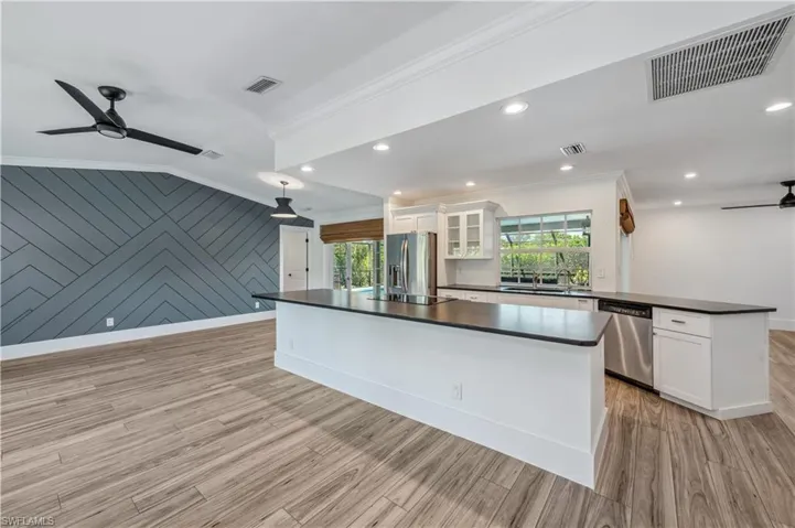 Kitchen with visible vents, ceiling fan, ornamental molding, stainless steel appliances, and dark countertops