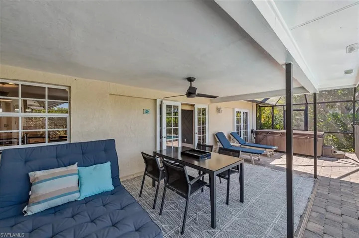 View of patio / terrace with a lanai, outdoor dining area, a ceiling fan, and a hot tub