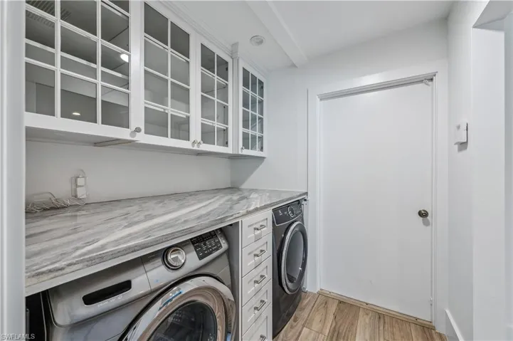 Laundry area featuring cabinet space, light wood-style flooring, and independent washer and dryer