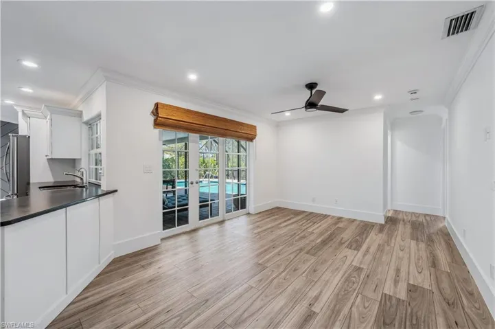 Unfurnished living room with ceiling fan, visible vents, light wood tile  finished floors, and a sink