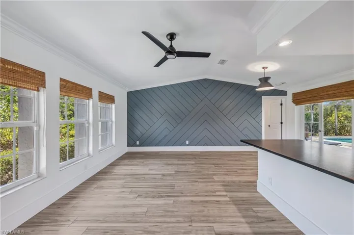 Unfurnished living room with light wood-style tile flooring, lofted ceiling, ceiling fan, and ornamental molding