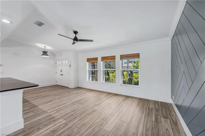 Unfurnished living room with visible vents, baseboards, ceiling fan, ornamental molding, and wood like tile floors