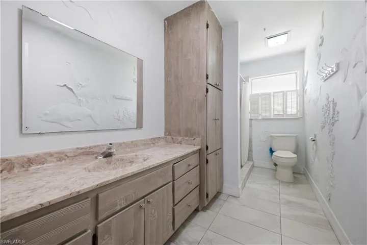 Bathroom featuring a double vanity with an integrated sink, a built-in linen cabinet, and a walk-in shower