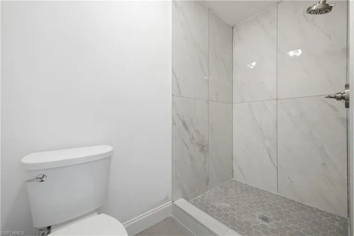 Walk-in shower featuring large format tile walls and a hexagonal tile floor