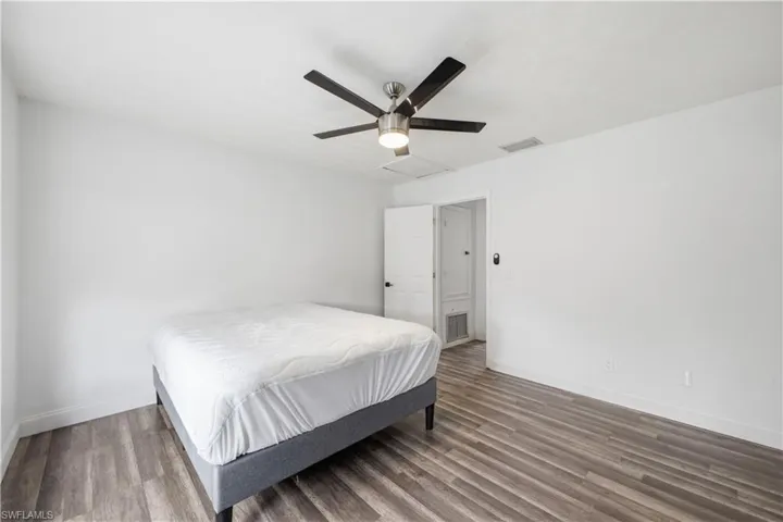 Bright interior space featuring wood-finish flooring, white baseboards, and a modern ceiling fan with five blades and a central light fixture