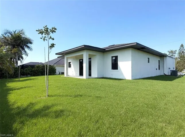 Rear view of house with a lawn, a patio area, and stucco siding