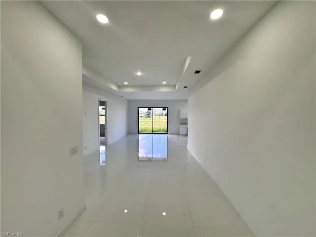 Hall with recessed lighting, a tray ceiling, and light tile patterned flooring