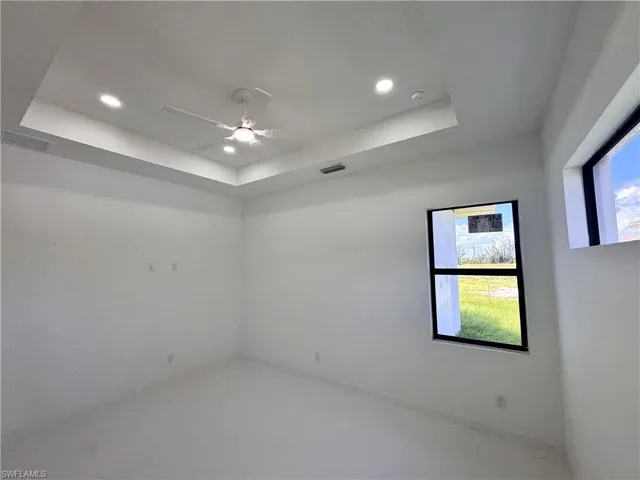 Spare room with a raised ceiling, recessed lighting, and ceiling fan