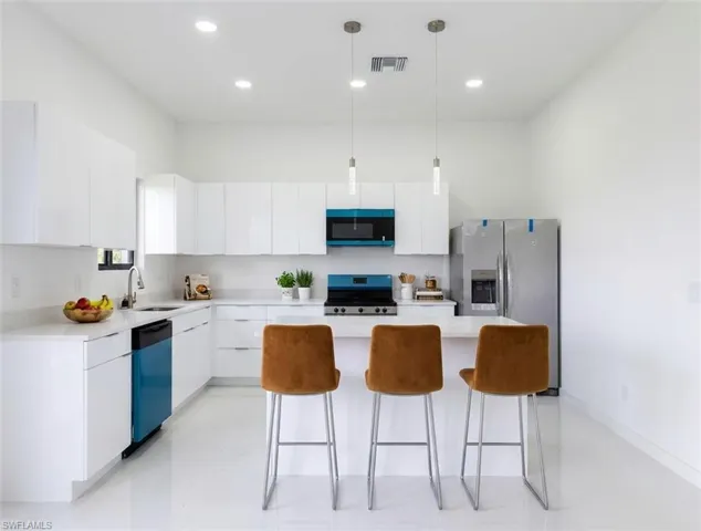 Kitchen with stainless steel fridge with ice dispenser, range, white cabinets, modern cabinets, and pendant lighting
