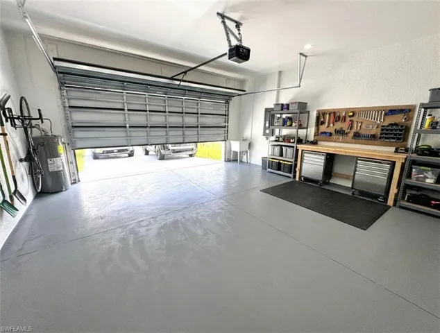 Garage featuring electric water heater, a garage door opener, and a workshop area