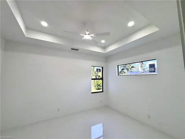 Empty room featuring a tray ceiling, a ceiling fan, and recessed lighting