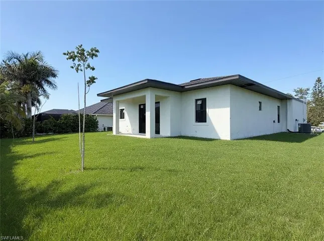 Rear view of property with a patio area, a lawn, and stucco siding
