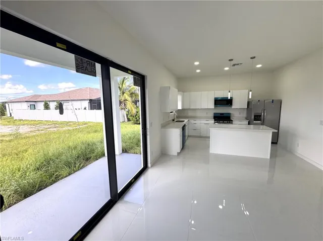 Kitchen featuring white cabinetry, a center island, decorative light fixtures, black appliances, and recessed lighting