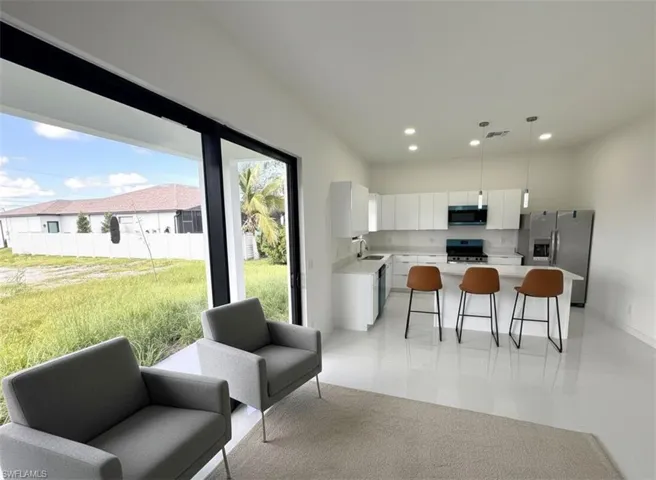 Kitchen featuring white cabinetry, black appliances, hanging light fixtures, recessed lighting, and a breakfast bar