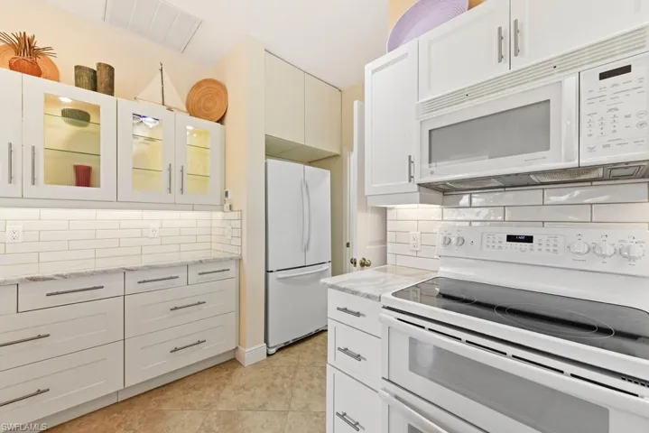 Kitchen featuring white cabinetry, white appliances, and light tile patterned floors
