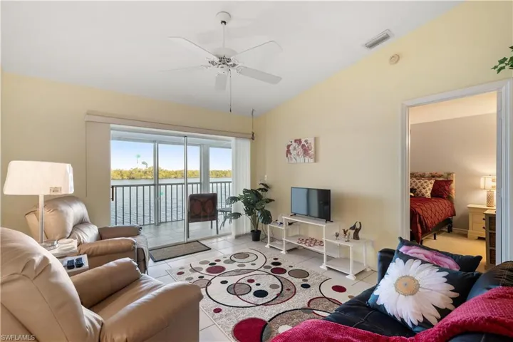 Living room with light tile patterned floors, vaulted ceiling, and ceiling fan
