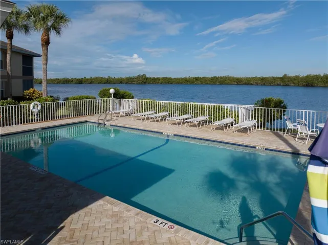 View of swimming pool with a water view and a patio area
