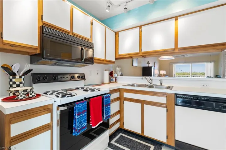 Kitchen featuring white cabinets, white appliances, and sink