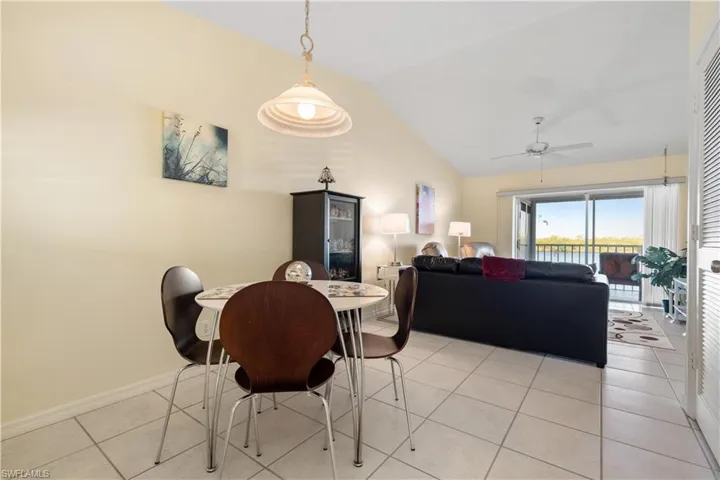 Dining area with light tile patterned flooring, vaulted ceiling, and ceiling fan