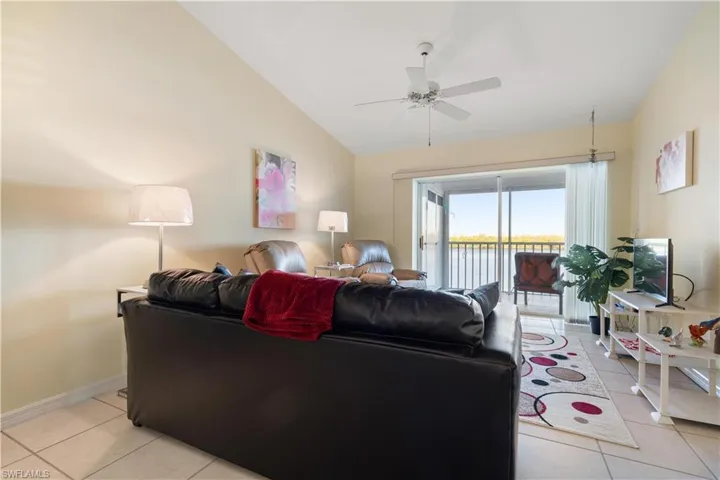 Living room featuring ceiling fan, light tile patterned floors, and vaulted ceiling