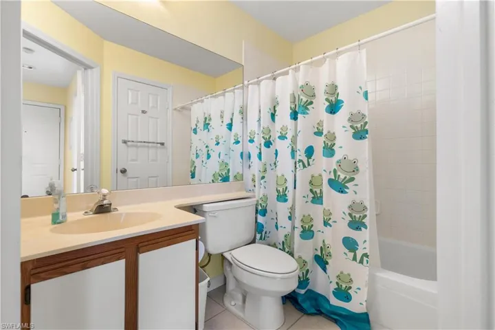 Full bathroom featuring shower / tub combo with curtain, vanity, toilet, and tile patterned floors