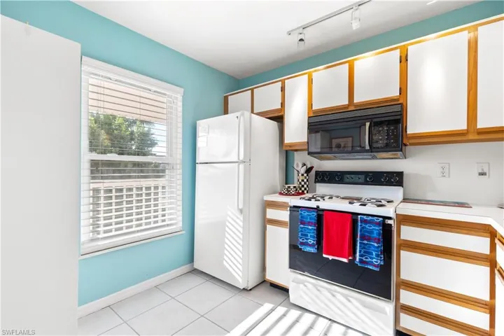 Kitchen featuring white cabinets, light tile patterned floors, white appliances, and rail lighting