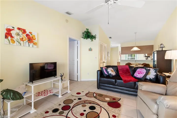 Living room with light tile patterned flooring, vaulted ceiling, and ceiling fan