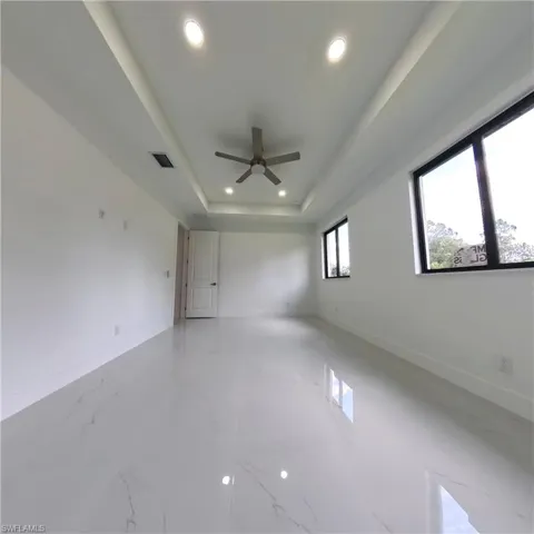 Unfurnished room with recessed lighting, a ceiling fan, baseboards, and a raised ceiling