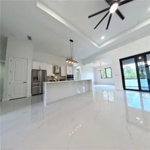Unfurnished living room with light marble finish floors, a chandelier, and a ceiling fan