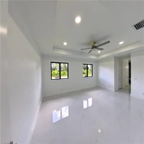 Unfurnished room featuring recessed lighting, a tray ceiling, ceiling fan, baseboards, and light marble finish floors