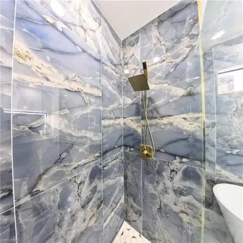 Full bath featuring a marble finish shower and a freestanding tub