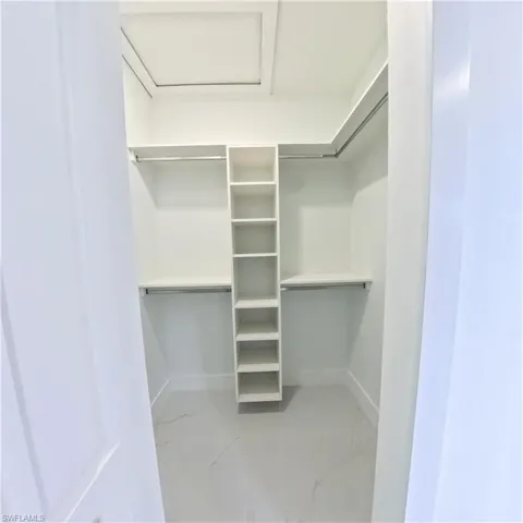 Spacious closet with light marble finish floors and attic access