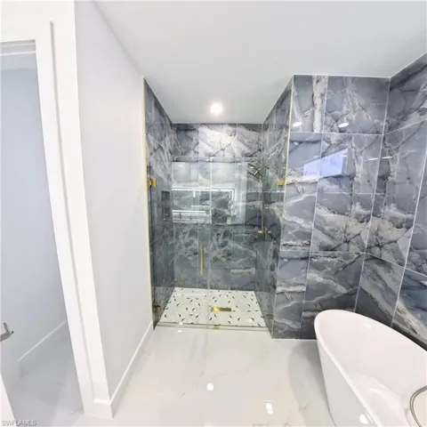 Bathroom with a marble finish shower and a freestanding bath