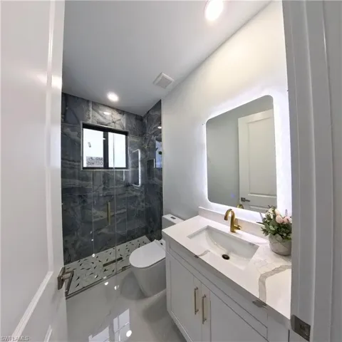 Full bathroom with a marble finish shower, toilet, vanity, marble finish flooring, and recessed lighting