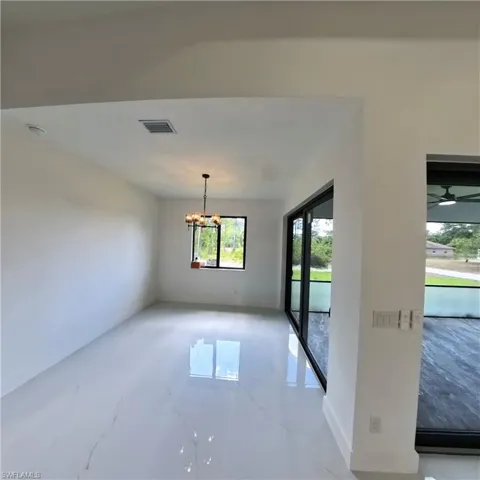Unfurnished dining area with a chandelier and light marble finish floors