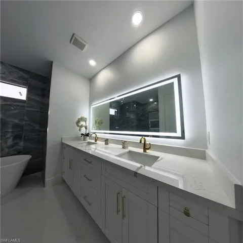 Bathroom featuring double vanity, a soaking tub, a shower, and recessed lighting