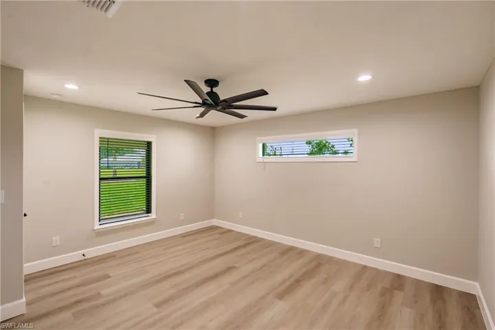 Empty room featuring light hardwood / wood-style floors, plenty of natural light, and ceiling fan