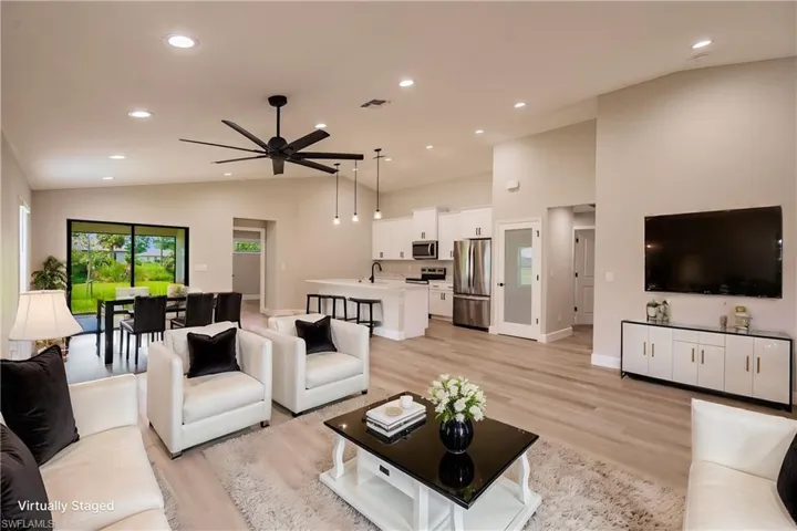 Living room featuring light hardwood / wood-style flooring, ceiling fan, sink, and vaulted ceiling